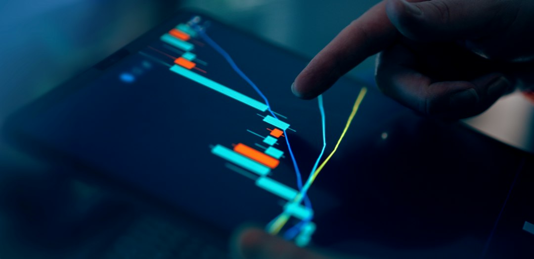 Close-up of a hand pointing at a colorful graph on a digital tablet
